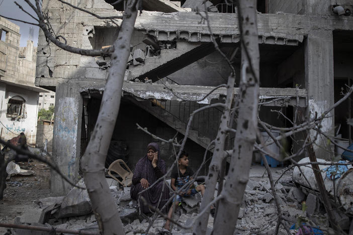 A Palestinian woman sits with her son in front of her destroyed house in the town of Beit Hanoun, northern Gaza Strip, to which she returned following a cease-fire reached after an 11-day war between Gaza's Hamas rulers and Israel.