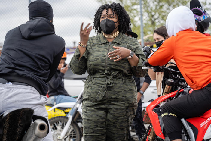 Brittany Young, CEO and founder of the nonprofit B-360, speaks with a couple of people from the neighborhood, who heard the dirt bikes and came to the parking lot to ride themselves.