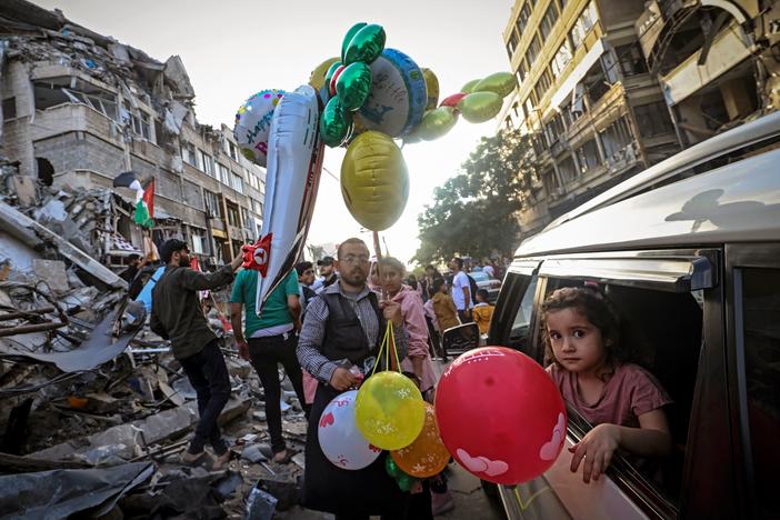 A Palestinian man sells balloons on Friday in Gaza City in front of the Al-Shuruq building, which was destroyed by an Israeli air strike.
