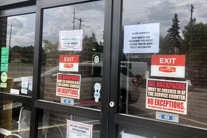 A sign on the front doors of Westlund's Apple Market in Lansing, Mich., asks customers to wear a mask unless they are vaccinated against COVID-19.