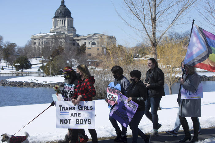 A new public survey reflects Americans' "mixed views" on trans issues, Gallup says, as people said athletes should compete based on the sex listed on their birth certificates. Here, protesters march against a bill restricting transgender girls from sports teams in Pierre, S.D., in March.