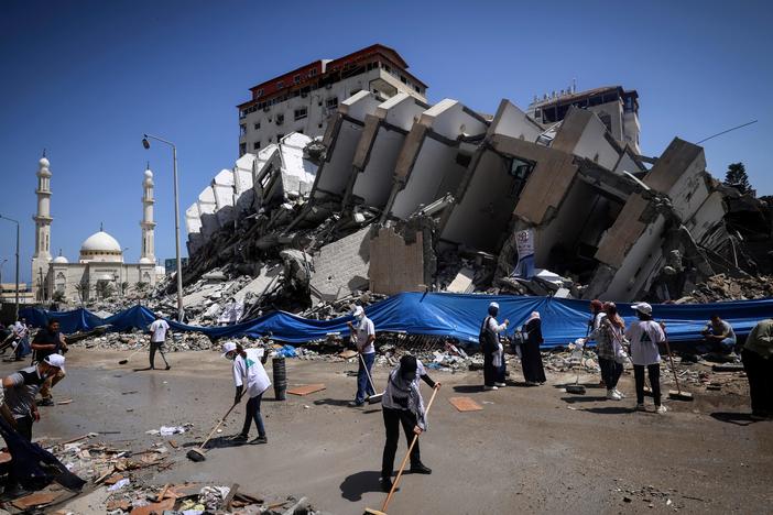 Palestinian volunteers and municipal workers clear the rubble of the Hanadi compound, recently destroyed by Israeli strikes, in Gaza City's Rimal district, on May 25, 2021.