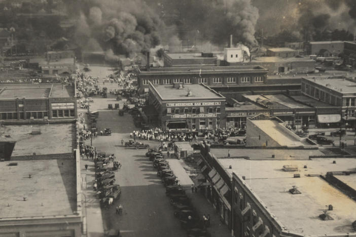 This archival photo shows crowds of people watching fires during the June 1, 1921, Tulsa Race Massacre.