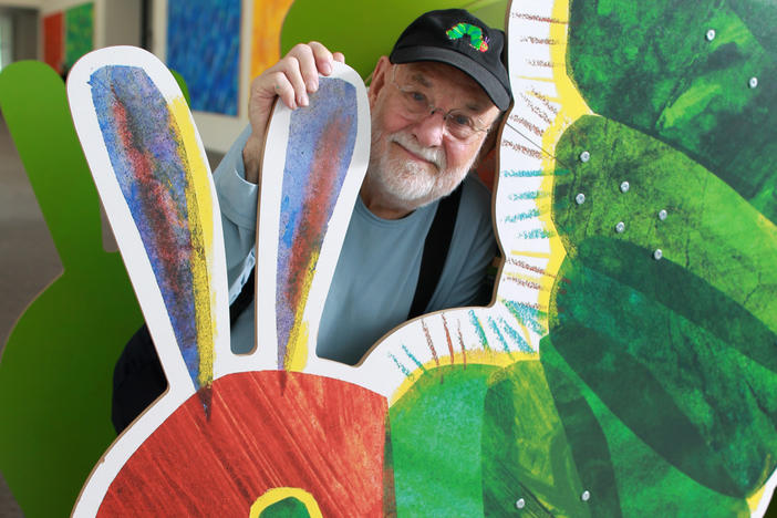 Eric Carle stands with large cutout of the iconic image from his children's book, "The Very Hungry Caterpillar," at The Eric Carle Museum of Picture Book Art in Amherst, Mass.