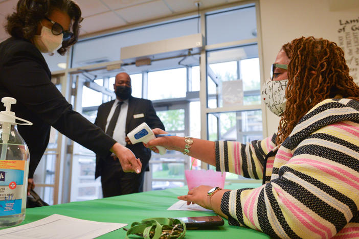 Yvette Richards, director of community connection at St. James United Methodist Church in Kansas City, Mo., checks temperatures before Sunday morning services. The church is hosting vaccination clinics and holding socially distanced services after shutting down for much of the pandemic.