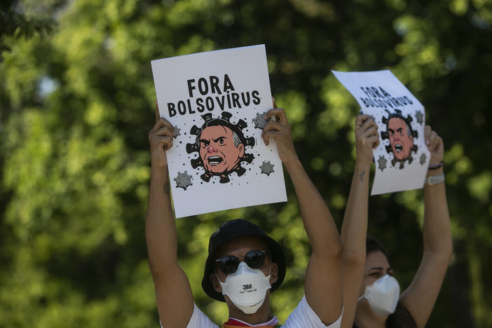 Demonstrators wearing protective face masks hold signs depicting President Jair Bolsonaro as a virus protest against the government's response in combating COVID-19, demanding the impeachment of Bolsonaro, in Rio de Janeiro, Brazil, Saturday, May 29, 2021.