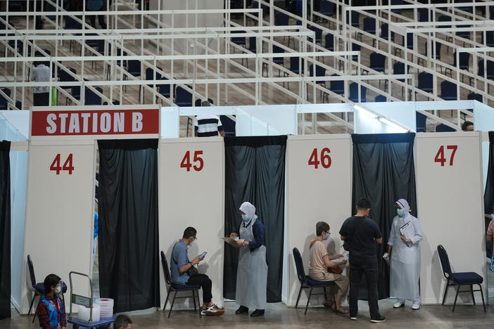 Health staff and patients at an exhibition center in Kuala Lumpur that's been turned into Malaysia's first mega-vaccination center. The government aims to speed up inoculations amid a sharp spike in infections.