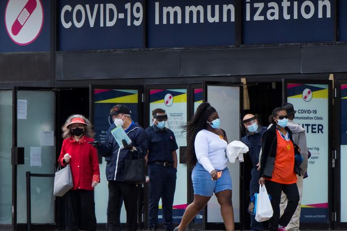 Canada's National Advisory Committee on Immunization is recommending allowing people to mix COVID-19 vaccine doses. Here, people walk past a vaccination clinic this week in Toronto.