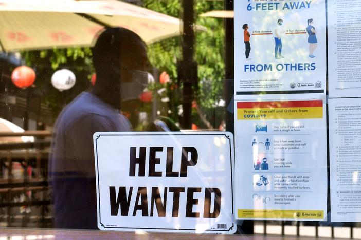 A "Help Wanted" sign is posted beside coronavirus health safety guidelines at a restaurant in Los Angeles on May 28. Businesses are desperate for workers even as millions remain unemployed. Republican governors blame a major unemployment benefit passed during the pandemic, saying it's dissuading people from rejoining the workforce.