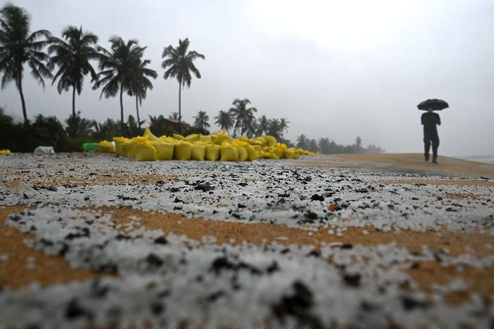A man walks past sacks containing debris washed ashore from the X-Press Pearl on a beach in Colombo on Thursday. The plastic pellets will break down and be more difficult to clean up over time, marine biologist Asha de Vos says.