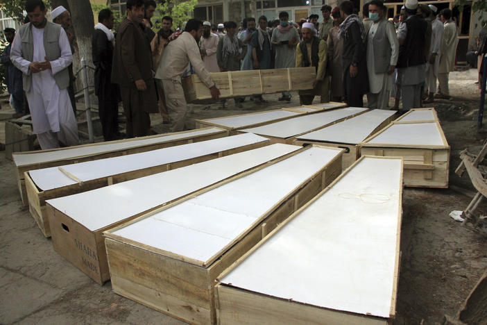 The coffins of the victims in Tuesday's attack are placed on the ground at a hospital in northern Baghlan province, Afghanistan, on Wednesday. Workers of the HALO Trust demining organization were attacked on Tuesday night by armed gunmen.