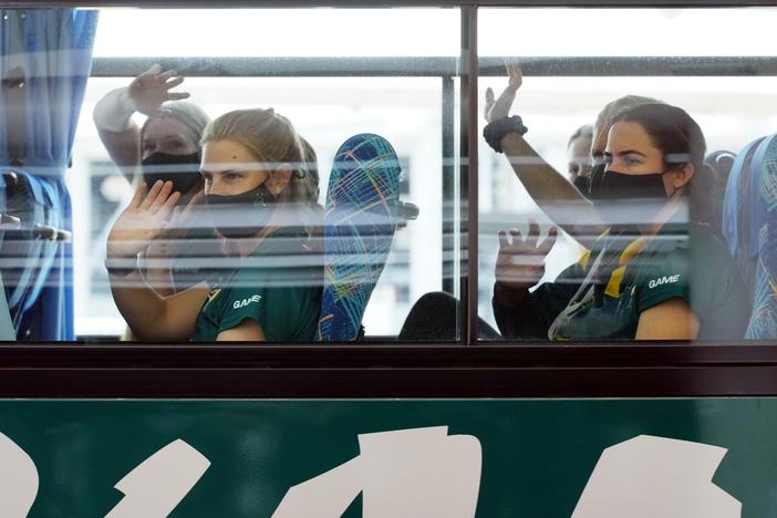 Australian softball players, the first foreign team to arrive for the Tokyo Olympic Games, wave from their bus after arriving at Narita International Airport on June 1.