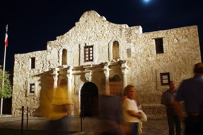 Visitors walk around the outside of the Alamo in San Antonio.