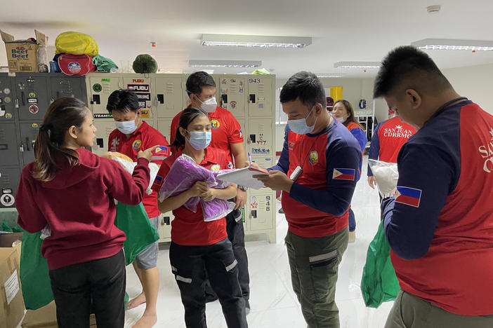 Staffers distribute the required personal protective gear before they transfer a COVID-positive patient to a hospital. They'll wear a gown, gloves, mask and face shield.