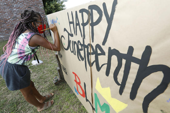 A girl paints on a poster celebrating Juneteenth in downtown Jackson, Miss., on June 19, 2020. Congress has voted to make the day a federal holiday.