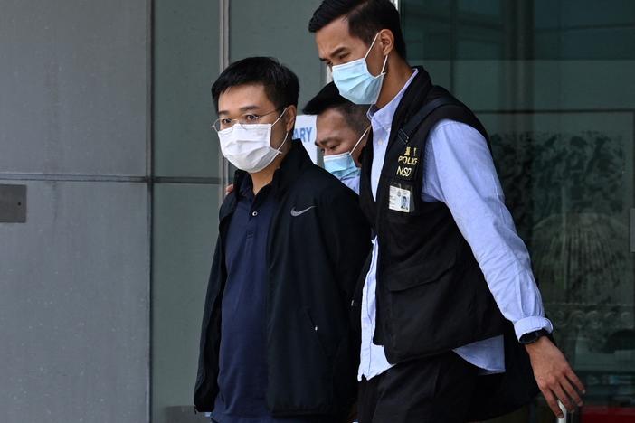 Apple Daily editor-in-chief Ryan Law is escorted by police to a waiting vehicle outside the entrance of the Apple Daily newspaper offices in Hong Kong on Thursday.