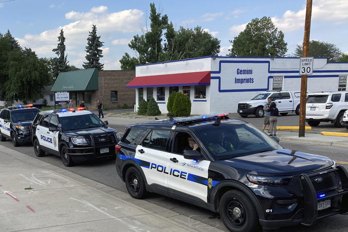 Police cars line up for a procession in honor of an officer who was fatally shot Monday in Arvada, Colo.