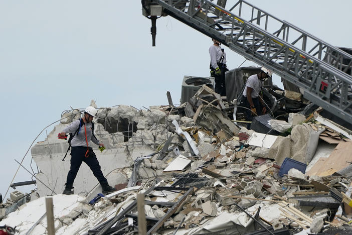 Rescue workers walk atop the rubble of a 12-story beachfront condo building that partially collapsed in Florida's Miami-Dade County.