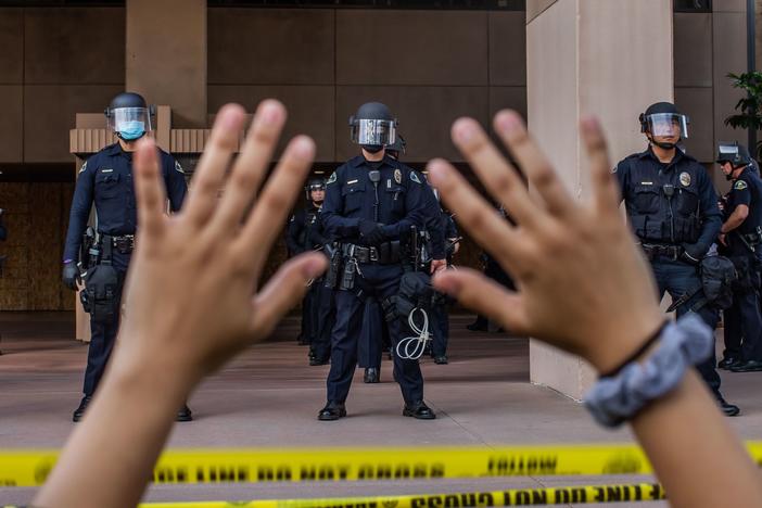 A demonstrator holds her hands up while she kneels in front of the Police at the Anaheim City Hall on June 1, 2020 in Anaheim, California. Reform pressures have many cops leaving the job.