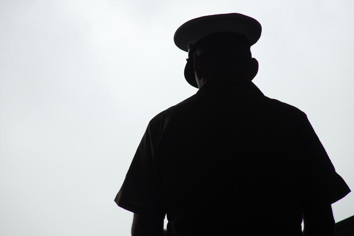 Silhouette of a U.S. Marine praying, photographed from behind.