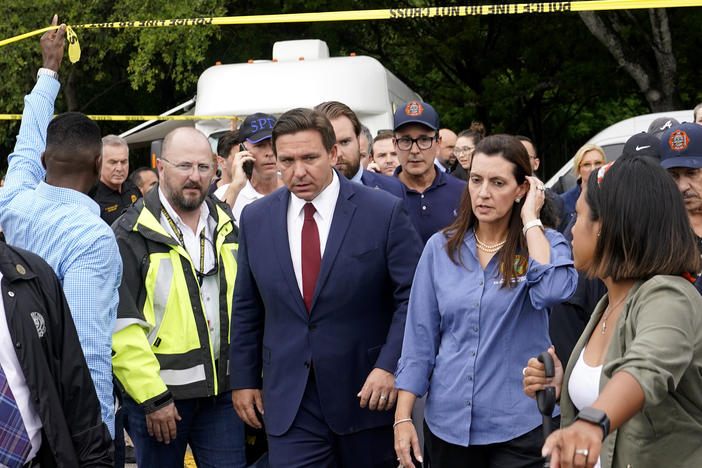 Florida Gov. Ron DeSantis (center) and Lt. Gov. Jeanette Nuñez (center right) arrive for a news conference near where a section of a 12-story beachfront condo building collapsed on Thursday in the town of Surfside.