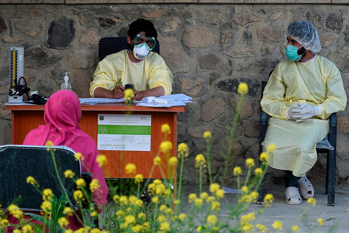 Medical staff wearing personal protective equipment register a suspected coronavirus patient in May at a Kabul hospital.