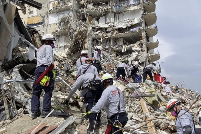 In this photo provided by Miami-Dade Fire Rescue, search-and-rescue personnel search for survivors through the rubble at the Champlain Towers South Condo in Surfside, Fla., on Friday.