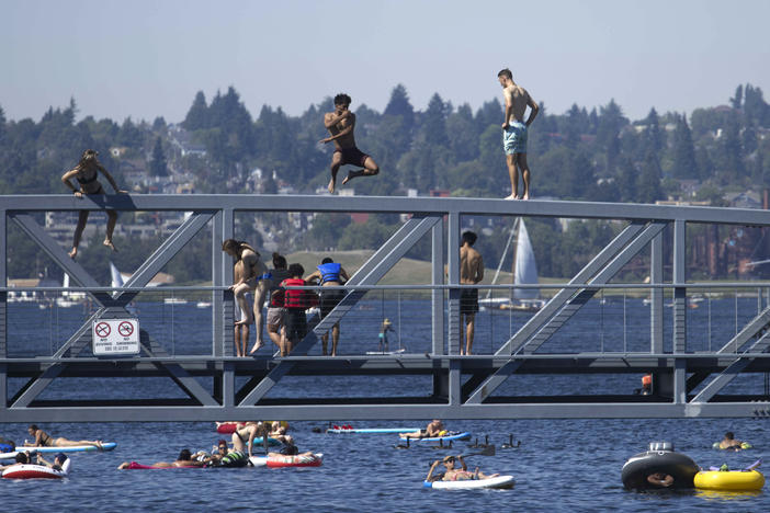 People jump from a pedestrian bridge at Lake Union Park in Seattle on Sunday as a record-setting heat wave blasts the Pacific Northwest.