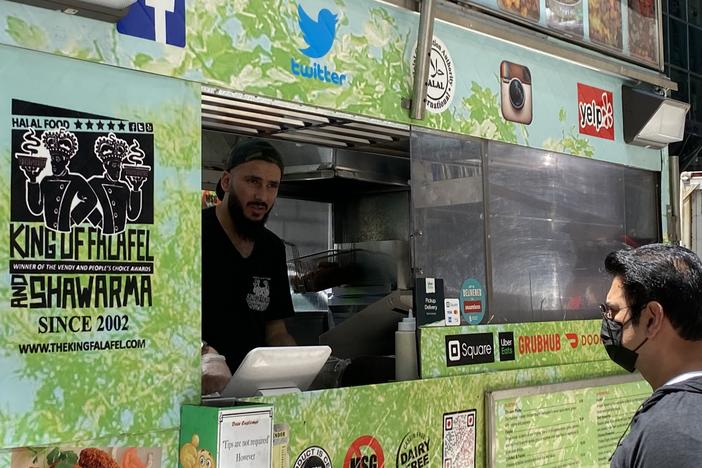 David Shadaha, who operates a cart called King of Falafel & Shawarma, takes an order from a customer in Midtown Manhattan, N.Y. Shadaha is back selling food after taking a job as a GrubHub deliveryman during the pandemic.