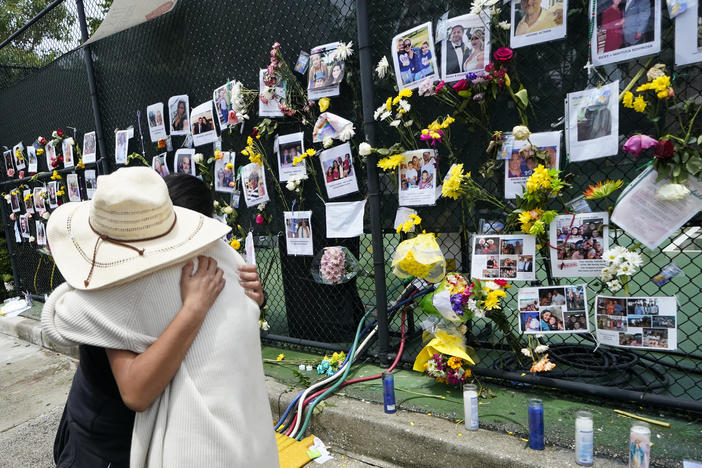 People embrace Monday at a makeshift memorial outside St. Joseph's Catholic Church in Surfside, Fla., near the site of the Champlain Towers South condo that partially collapsed last week.