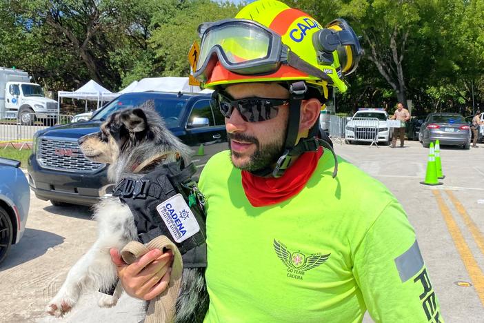 Moises Soffer, a volunteer member of Cadena International's search-and-rescue team working at the site of the condo building collapse, holds a trained search dog named Oreo in Surfside, Fla., on Sunday.