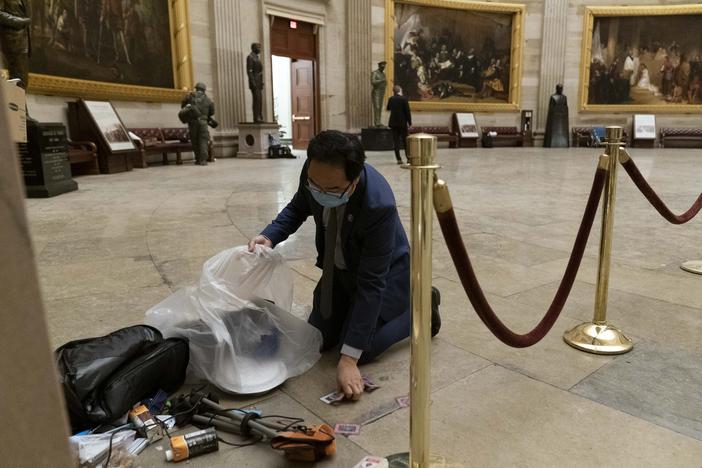 Rep. Andy Kim, D-N.J., cleans up debris and personal belongings strewn across the floor of the Rotunda in the early morning hours of Thursday, Jan. 7, 2021, after protesters stormed the Capitol in Washington, on Wednesday. (AP Photo/Andrew Harnik)