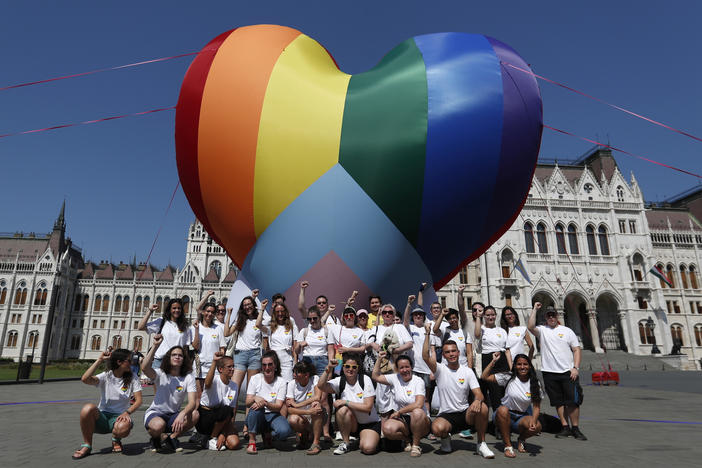 Activists pose for a photo after raising a large rainbow heart in front of Hungary's parliament building in Budapest on Thursday. The activists are protesting against a new law they say discriminates against and marginalizes LGBTQ people.