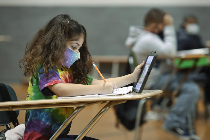 Masks are critical in reducing the risk of COVID-19 transmission for children too young for vaccines, such as this 7-year-old girl. That's part of the newly updated CDC guidelines for the coming school year — and for travel plans parents are making for summer.