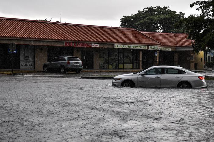 A woman drives through floodwater during heavy rainfall in Miami. A new study predicts that high tide flooding in coastal areas could increase in frequency because of climate change and the lunar cycle in the mid-2030s.