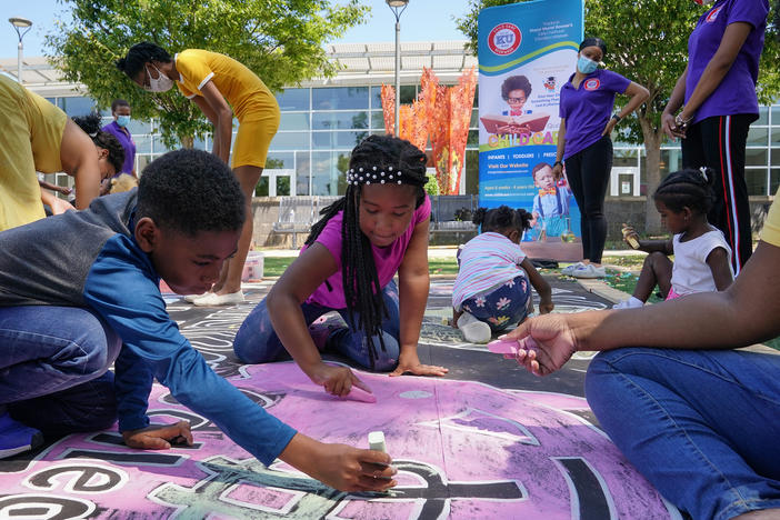 Children and teachers from the KU Kids Deanwood child care center in Washington, D.C., complete a mural in celebration of the launch of the child tax credit.