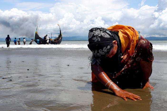 An exhausted Rohingya refugee woman touches the shore after crossing the Bangladesh-Myanmar border by boat through the Bay of Bengal, in Shah Porir Dwip, Bangladesh, on Sept. 11, 2017.