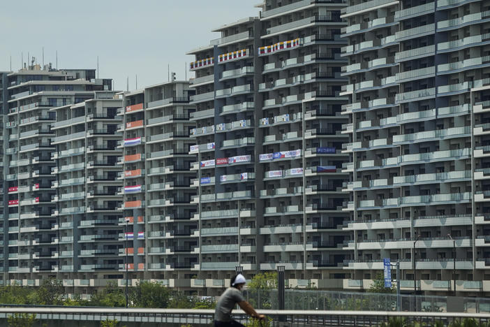 A man rides a bike near the village for the Summer Olympics in Tokyo. On Saturday, officials announced the first case of COVID-19 found at the center housing thousands of athletes.