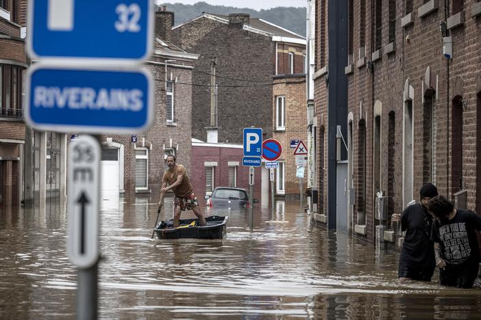A man rows a boat down a residential street after flooding in Liège, Belgium, on Friday.