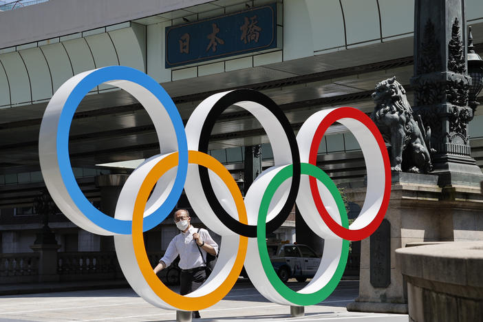 A man wearing a face mask walks past the Olympic Rings ahead of the Tokyo 2020 Olympic Games. The Games are scheduled to begin this week in Japan despite a global rise in coronavirus cases.