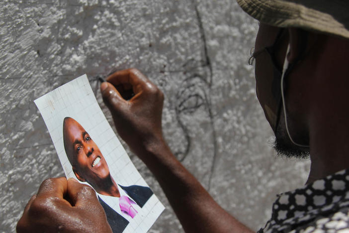 An artist who goes by the name Jamesy Jay paints a mural of slain Haitian president Jovenel Moïse on the road leading to the president's private residence above Port-au-Prince.