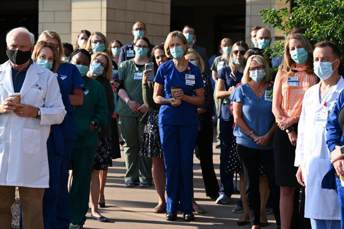 Front-line workers at a medical center in Aurora, Colo., gather for a COVID-19 memorial on July 15 to commemorate the lives lost in the coronavirus pandemic. New estimates say many thousands more will die in the U.S. this summer and fall.