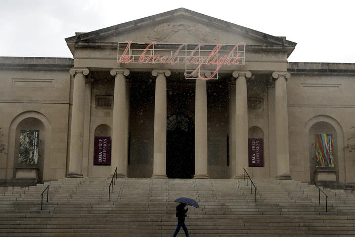 A man covers himself from rain with an umbrella as he walks by the Baltimore Museum of Art on April 21, 2020. An upcoming exhibit at the museum will be curated by security guards.