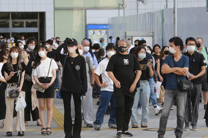 People wearing face masks to protect against the spread of the coronavirus stand at an intersection in Tokyo on Tuesday.