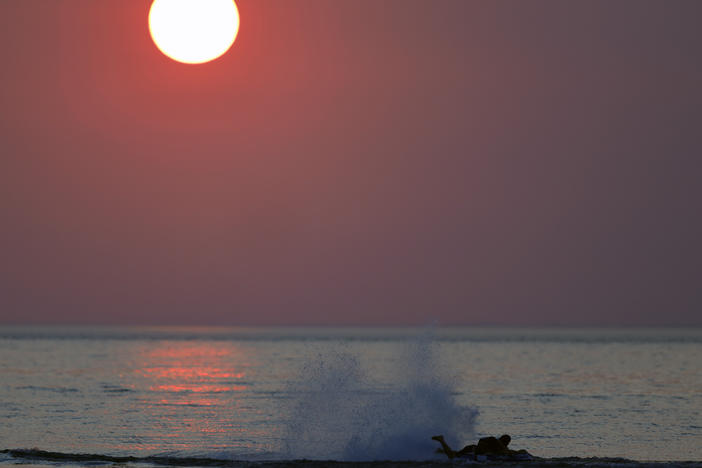 Western wildfires create a hazy sky as a person surfs on the water in Indiana Dunes State Park on Tuesday.