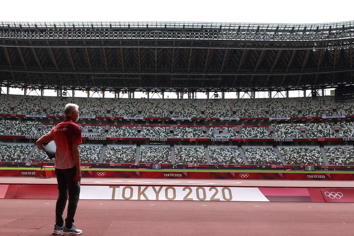 A passerby looks on while wearing a protective face covering inside an empty Olympic Stadium, host to the Athletics competition, at the Tokyo Olympic Games on Thursday.