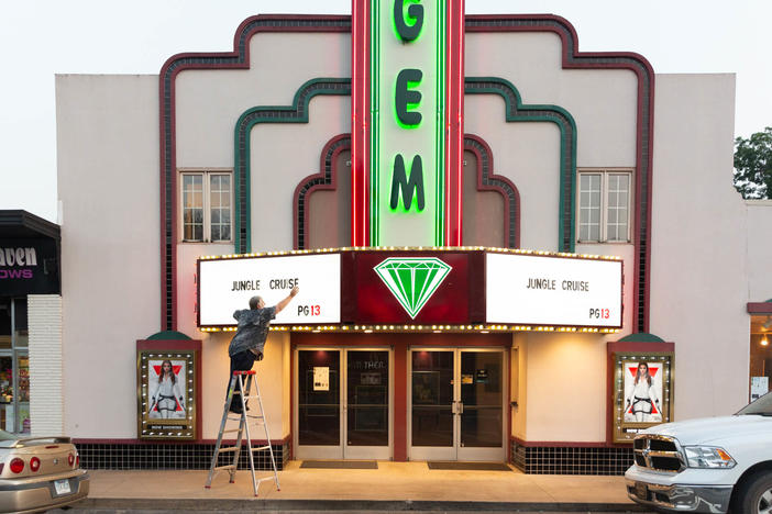 Kenny Nations, manager of the movie theater, changes the sign on the marquee; he is fully vaccinated and has tried to encourage co-workers to follow suit.
