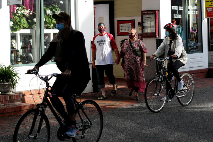 Pedestrians and cyclists head down Commercial Street in Provincetown, Mass., in May 2020. A study of a new outbreak in Provincetown found that three-quarters of those infected with the virus were fully vaccinated.