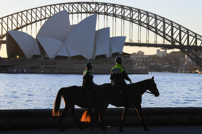 Mounted police officers patrol around the edge of Sydney Harbor on Friday as the Australian city has been locked down amid a new surge in coronavirus infections.