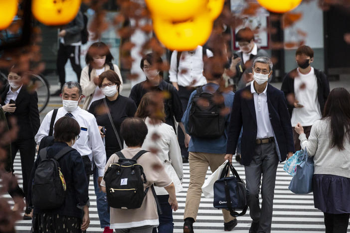 People in Tokyo wear masks on May 7. Daily coronavirus infections in Japan's capital have topped 4,000 — nearly four times as many as a week ago.